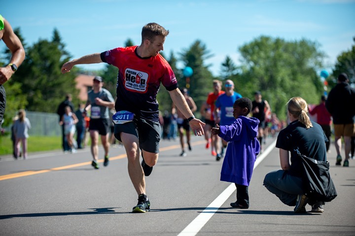 A marathon runner high-fives a child watching on the side of the road